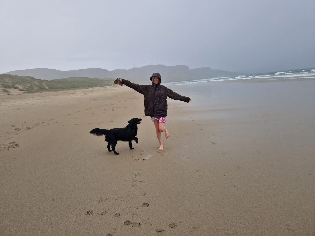 Girl and dog in rain on beach